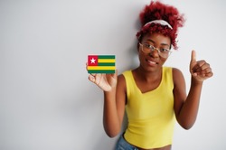 African woman with afro hair, wear yellow singlet and eyeglasses, hold Togo flag isolated on white background, show thumb up.