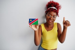 African woman with afro hair, wear yellow singlet and eyeglasses, hold Namibia flag isolated on white background, show thumb up.