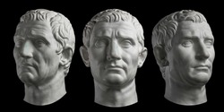 Three gypsum copy of ancient statue head of Guy Julius Caesar isolated on black background. Plaster sculpture man face.