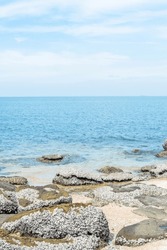 Beautiful rocky seashore with splashes of sea waves and White Sandy beach,sea shore with big stones and blue sky.