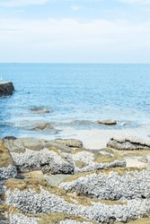 Beautiful rocky seashore with splashes of sea waves and White Sandy beach,sea shore with big stones and blue sky.