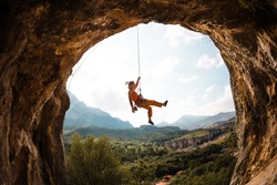 Rock climber hanging on a rope. A woman climbs a rock in the shape of an arch. The girl climbs in the cave. Climbing rope for belaying. Rock climbing in Turkey .