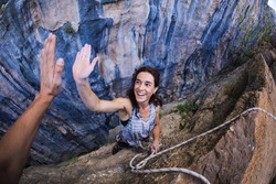A woman is climbing in Turkey, Turkish woman climbs the rock, Extreme hobby, Overcoming a difficult climbing route, Overcoming the fear of heights, Emotional girl gives five to a friend.