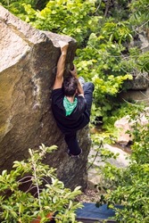 Bouldering on natural terrain, a strong man climbs a boulder, a man goes in for sports in nature, an effort to overcome
