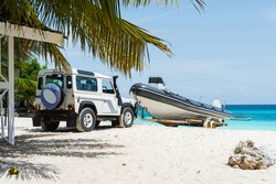 seascape with car transporting motorboat on african sandy beach