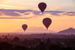 Hot air balloons fly over the ancient pagodas of old Bagan in Myanmar at sunrise. Bagan, Myanmar.