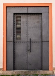 Metal doorway entrance into building in Old Town Prague. Massive strong secure doors, with orange bordering and stone step. 