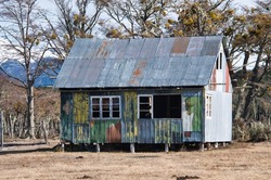Forgotten and abbandoned house made of wood and metall with remains of a colorful paint that is now fainted, standing in the middle of nowhere in Patagonia, Chile. 