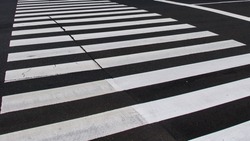 Abstract picture of a pedestrian crosswalk on a street in Tokyo, Japan with diagonal white stripes that have cracks and show signs of weathering. Abstract background for presentation or desktop.