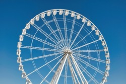 Big, tall white Ferris wheel in front of a perfect blue sky at the oceanfront in Marseille, France. Happy summer vacation feelings. 