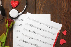 Top view valentines day love song music background and decorations.heart shape,music note paper,flower on wooden with copy space.Create this music note paper myself.