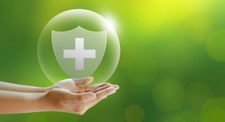 Hand offer medical shield on green background. Family life insurance, Medical care insurance, and Business healthy concepts. 