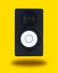 Pair of professional high quality monitor speakers for sound recording, mixing, and mastering in studio in black wooden casing isolated on yellow background. Front or Side view.