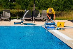 The cleaner turns on an automatic cleaning robot to clean the pool. Automatic pool cleaning. Concept photo  pool cleaning, hotel staff, service.
