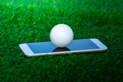close up the golf ball on the smartphone in green grass background