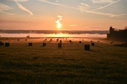 Sunrise over the lake with haybales. Mist rising over the lake with sunrise. 