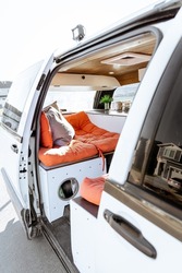 Beautiful bright natural light entering and illuminating an old self converted minivan campervan for van life. The vanlife recreational vehicle has orange seat cushions, stained roof, and van plant.