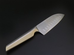 A large kitchen knife on a dark background. Knife with a wide shar blade isolated on black background. Unused professional chef knife. Cutting utensils. Chef knife. Kitchen utensils isolated.