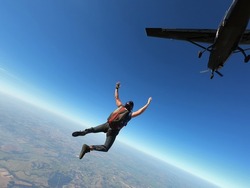 Skydiver jumps from a black plane on a hot day with clear skies.