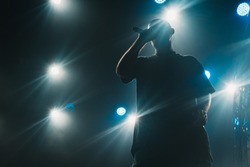 A silhouette of a singer on the stage. Good-looking background, bright stage lights. 