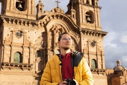 Tourist in the main square of cuzco, holding his camera, with a church in the background.