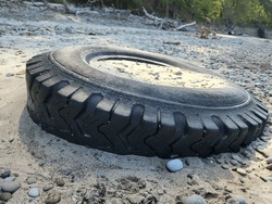 Car or Truck Tire Laying on Beech with Sand inside