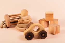 Children's wooden toys on a pink background. Cubes, pyramid, car. The concept of children's education and early development according to the Montessori method. Natural eco-friendly materials.