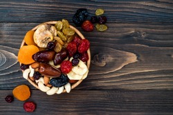 Mix of dried fruits and nuts on a dark wood background with copy space. Top view. Symbols of judaic holiday Tu Bishvat