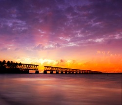 Beautiful colorful sunset or sunrise with broken bridge and sun rays spreading through purple clouds. Taken at Bahia Honda state park in the Florida Keys, near famous tourist destination of Key West.