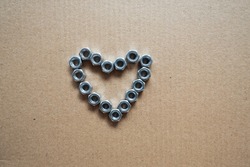 Top view heart lined with metal fittings, nuts, bolts, screws with empty space inside on brown background, steel heart valentine, metal heart for valentines day