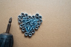 Heart lined with metal fittings, nuts, bolts, screws and drill bits with blank space with brown background, steel heart valentine, metal heart for valentine's day