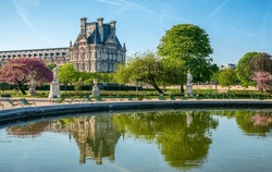 Panoramic view of the Tuileries Park with pond, flowers, statues, fountain, and cherry blossoms during April - springtime in Paris, France.