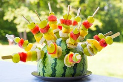 Watermelon decorated with colorful fruit skewers, with shallow depth of field.