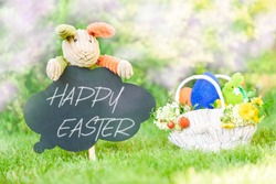 Happy Easter text on blackboard and basket with Eastertide symbols