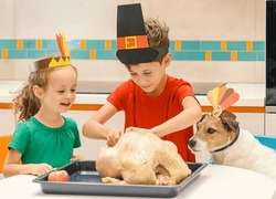 Children and dog wearing Thanksgiving costumes stuffing holiday turkey with apples