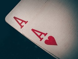 Macro shot texture of playing cards. A pair of aces on a black background. Ace of hearts and ace of diamonds. Nuts hand a pair of aces to win. Close-up image a pair of aces.