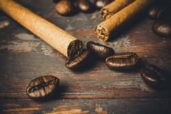 Concept of unhealthy lifestyle, unhealthy breakfast. Three cigarettes lying on a roasted coffee beans. Composition with cigarettes and coffee beans. High quality photo