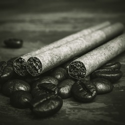 Concept of unhealthy lifestyle, unhealthy breakfast. Three cigarettes lying on a roasted coffee beans, black and white Photo. Composition with cigarettes and coffee beans. . High quality photo
