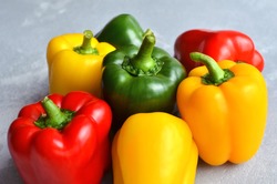 Green, red and yellow bell pepper on grey stone background. Organic healthy food