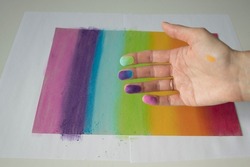 Hands stained with pastel crayons. A woman artist paints a picture of the colors of the rainbow.