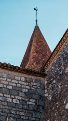 Long shot of church tower with a weathercock in small french village, south of france at Monpazier, near to the castles of Biron