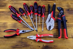 Set of different pliers and screwdrivers on wooden background. Top view