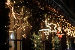 Stylish christmas star illumination and spruce branches in golden lights in evening, fairytale decoration. Atmospheric magic time. Christmas festive decor for winter holidays in city street