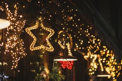 Stylish christmas star illumination and spruce branches in golden lights in evening, fairytale decoration. Atmospheric magic time. Christmas festive decor for winter holidays. Merry Christmas!
