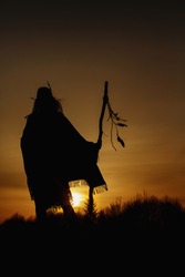 silhouette of woman shaman with pikestaff on background of sunset beautiful in mountains