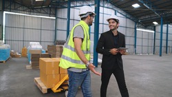 Factory workers deliver boxes package on a pushing trolley in the warehouse . Industry supply chain management concept .