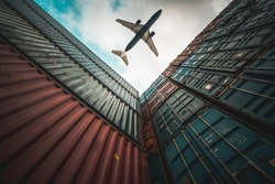 Freight airplane flying above overseas shipping container . Logistics supply chain management and international goods export concept .