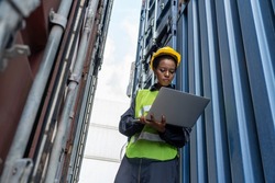 Young African American woman worker at overseas shipping container yard . Logistics supply chain management and international goods export concept .