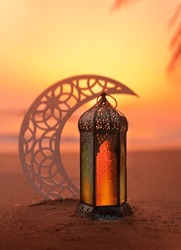 Ramadan Lantern on the beach with crescent moon shape during sunset, 2023 Islamic concept image, Eid Mubarak Greeting background