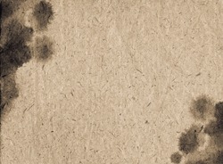 A sheet of old vintage paper stained with blotches of black watercolor paint. Fine grunge artistic background for creative design. Scan of brown aged textured paper with black ink blots.
